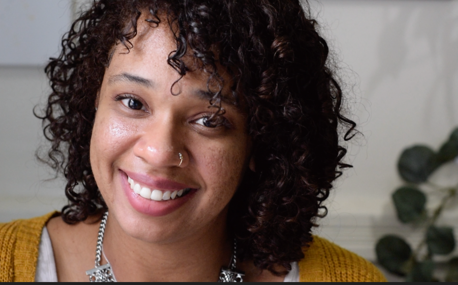image of Black woman with curly hair smiling at the camera.