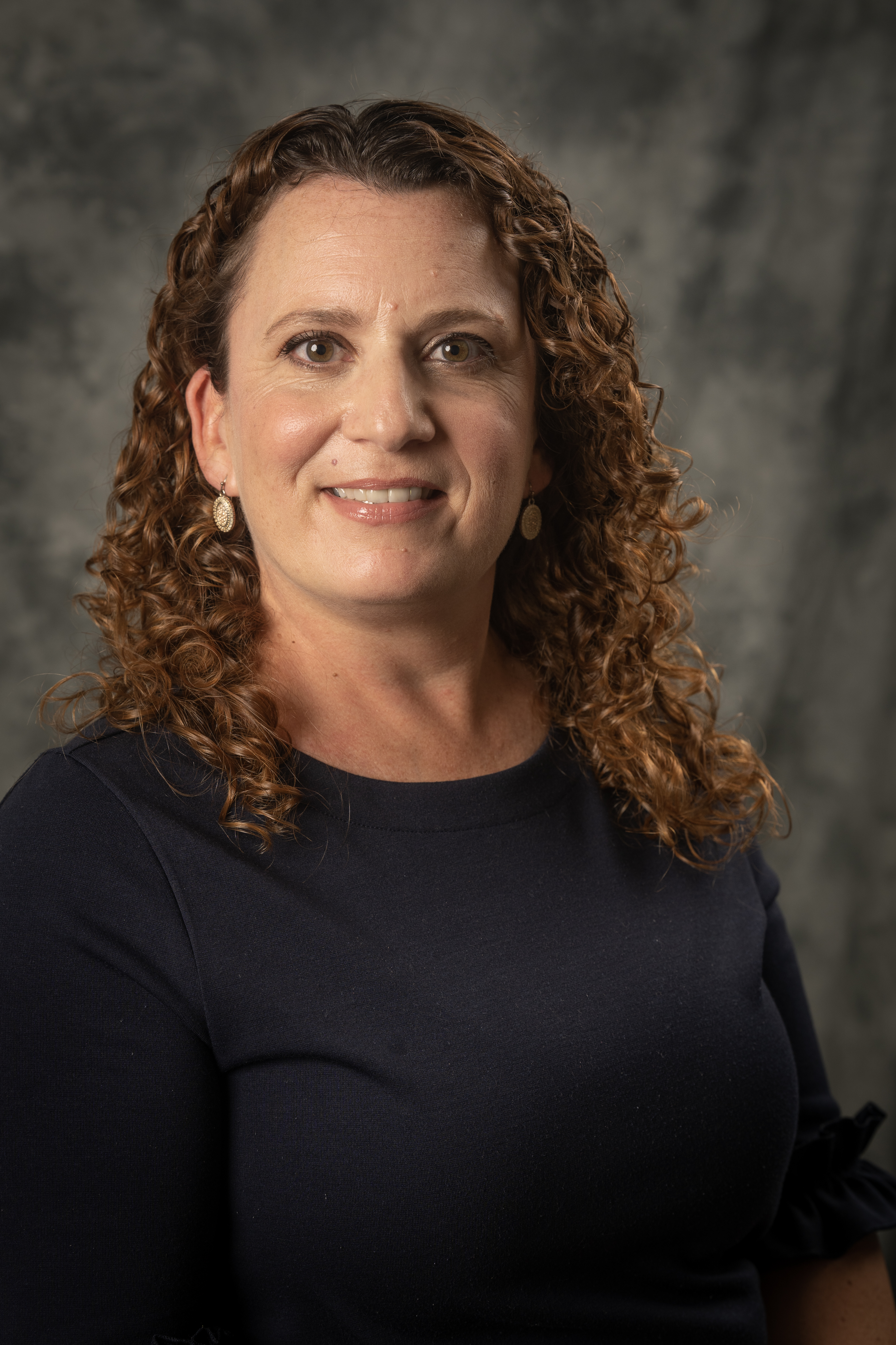 Lauren Donovan, with a black shirt and curly brown hair smiling