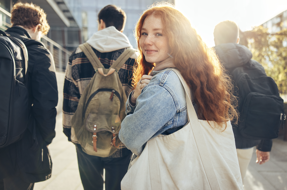 a high school student walks in to the school building smiling