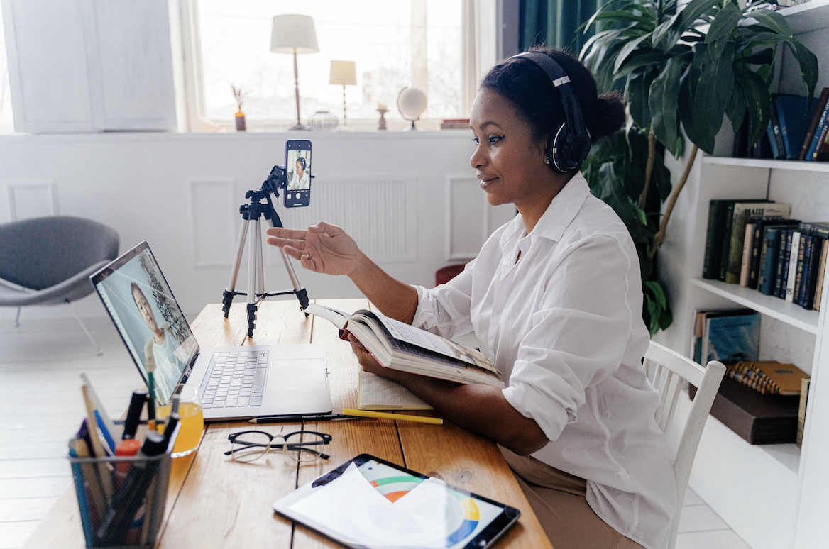 A woman teaches remotely while a child attends class virtually