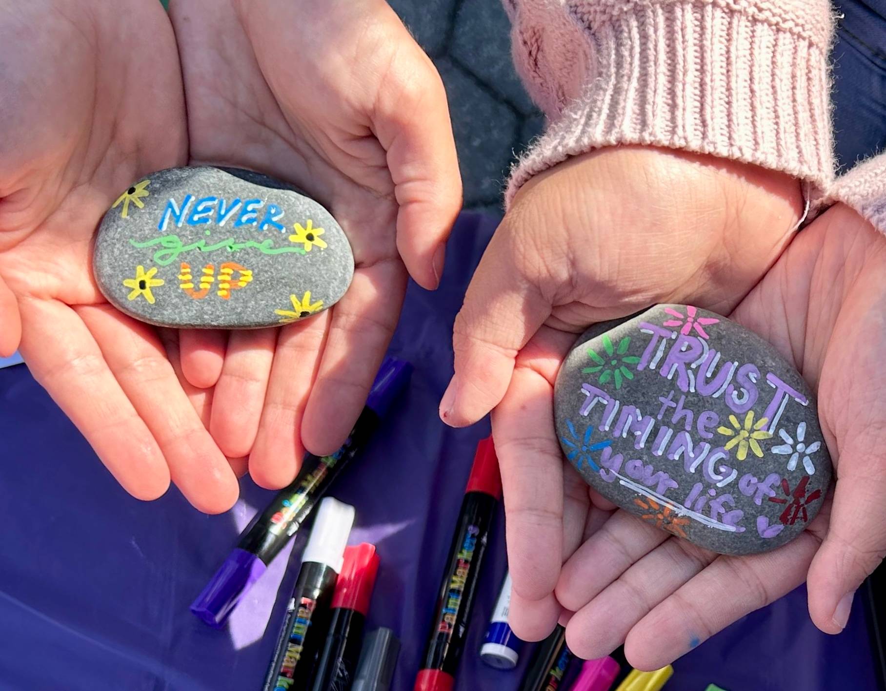 Students holding rocks of hope from our Fall 2024 event that say "Trust the Timing of Your Life" & "Never Give Up"